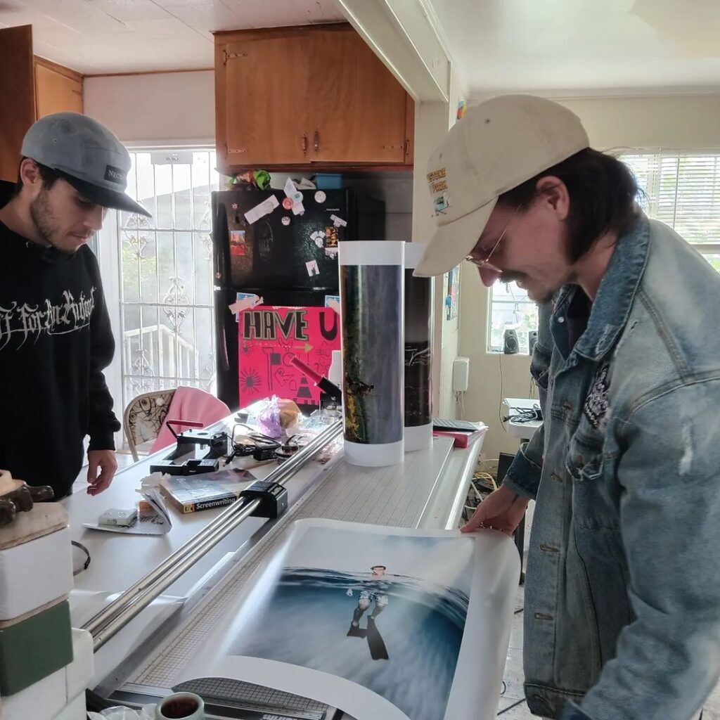 Two men examining a photograph in a bright kitchen.