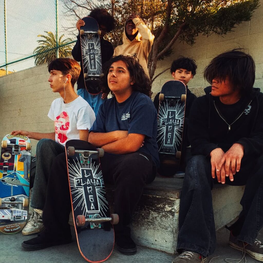 Four young people with skateboards sitting outdoors, relaxing.