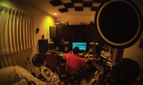 Person working in a dimly lit music studio with recording equipment.