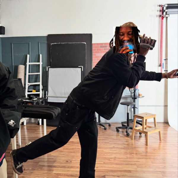 A person in black dancing joyfully in a studio.