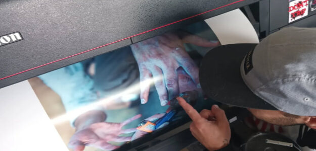 Person pointing at a laptop screen showing a colorful hand image.