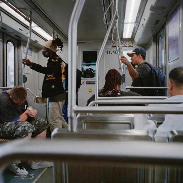 People riding a subway train with one person standing and holding a pole.